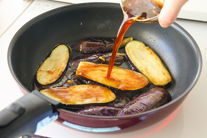 なすの生姜焼きで調味料を加えている写真