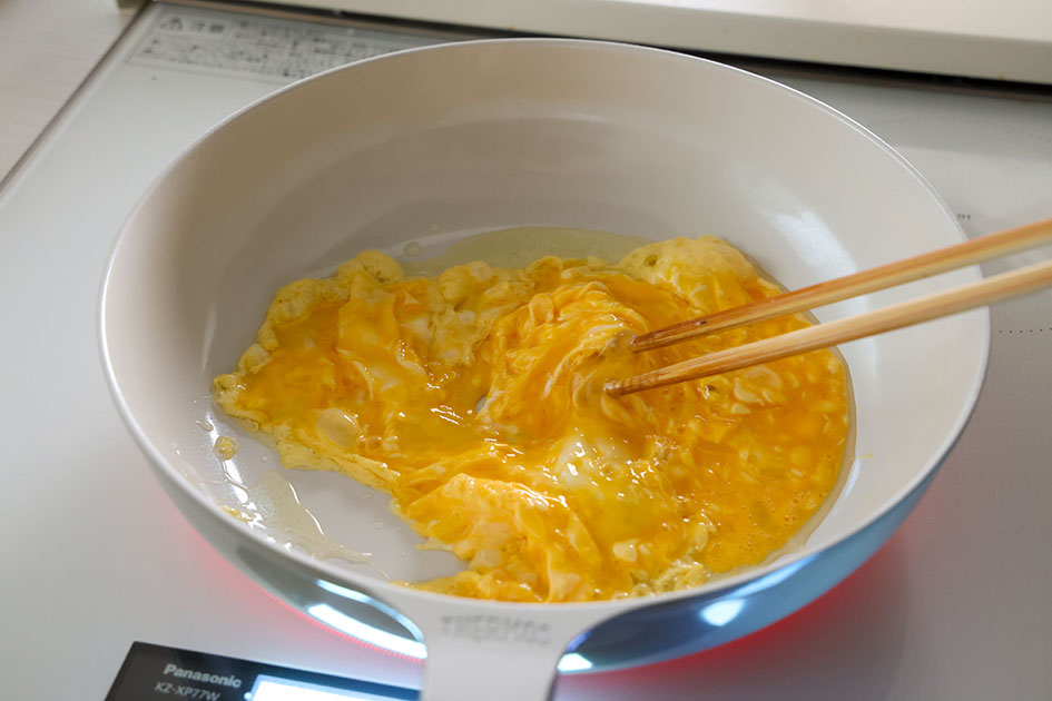 ほうれん草とベーコンの卵炒めで、卵を半熟状に炒めている写真