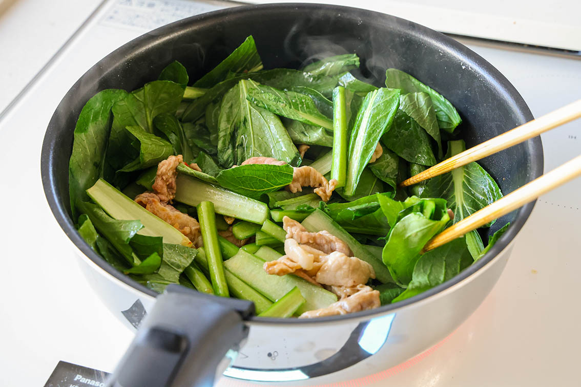 豚肉と小松菜のピリ辛中華炒めで、材料を炒めている写真