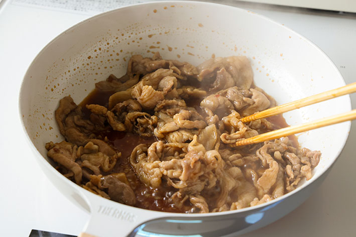 豚こまキャベツマウンテンで、炒めた豚肉にたれを煮からめている写真