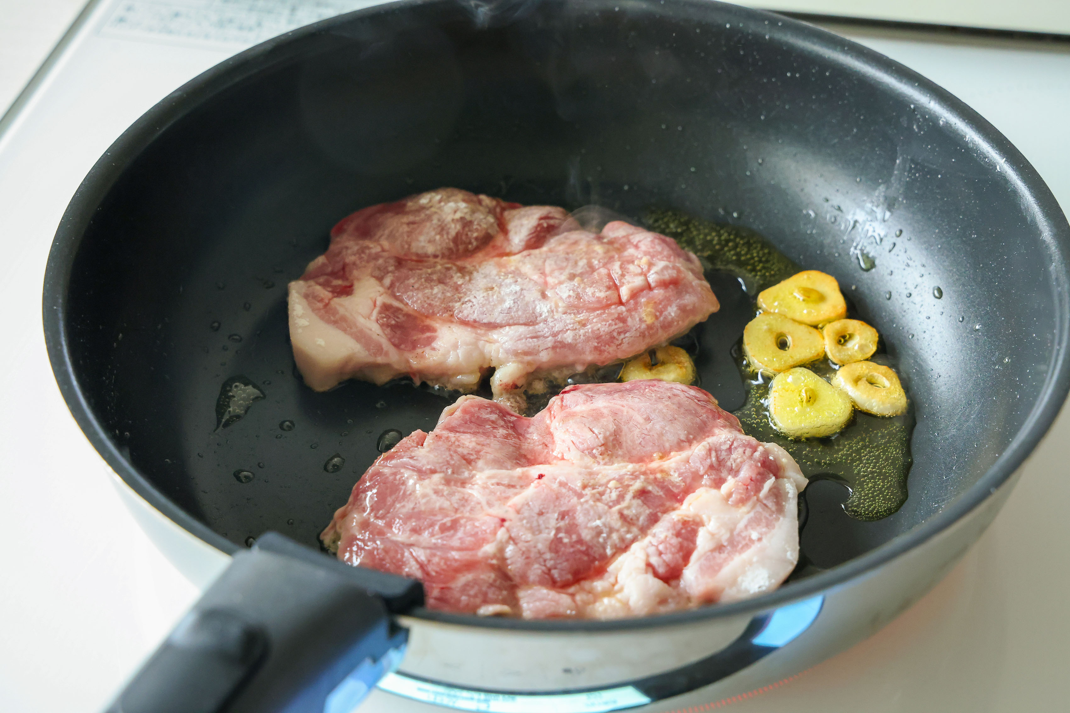 ポークソテー　フレッシュトマトソースで豚肉を焼いている写真